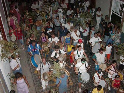 Imagen nocturna de la Bajada de La Rama de Las Marías de Guía, por la calle Pérez Galdós del casco del municipio. Personas con bucios, tambores y ramas.